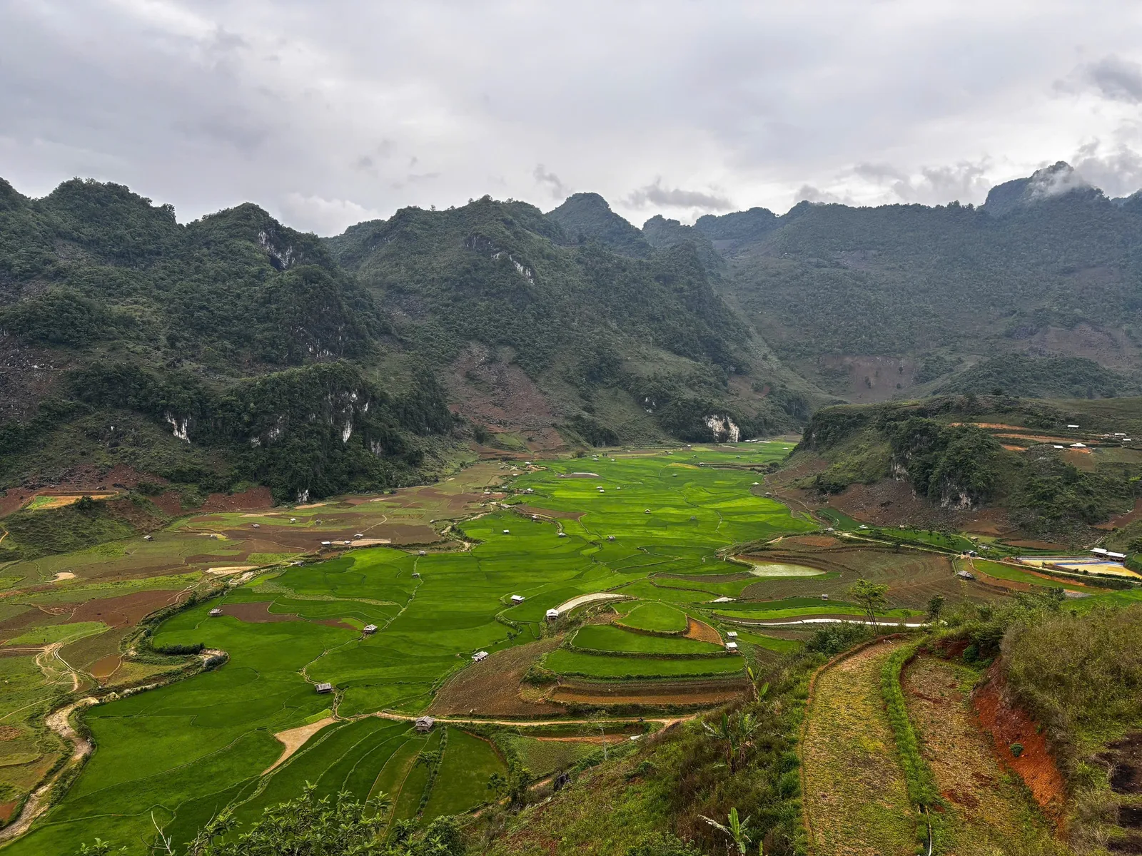 A lush green valley of rice fields surrounded by karst mountains near Dien Bien Phu, Vietnam.