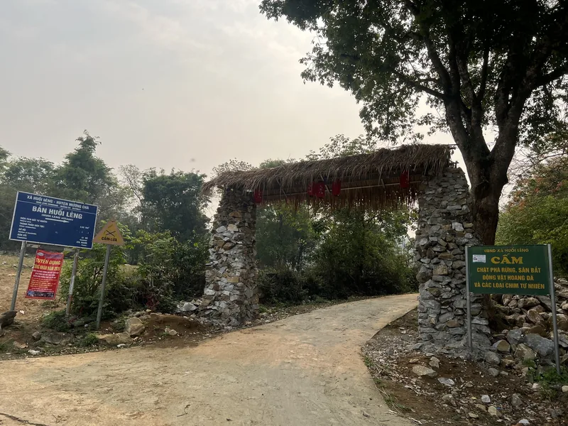 A rustic stone gate with a thatched roof marks the entrance to Ban Nuoi Leng village in Dien Bien province.
